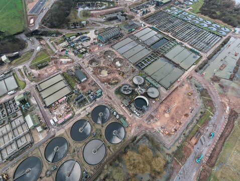 Aerial view of the stark geometry of the water treatment plant, where circular tanks contrast with rectangular settling basins, creating an industrial landscape, Leicester, England, United Kingdom.