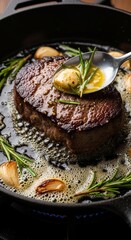Juicy pan-seared filet mignon with garlic, rosemary, and melting herb butter in cast iron skillet