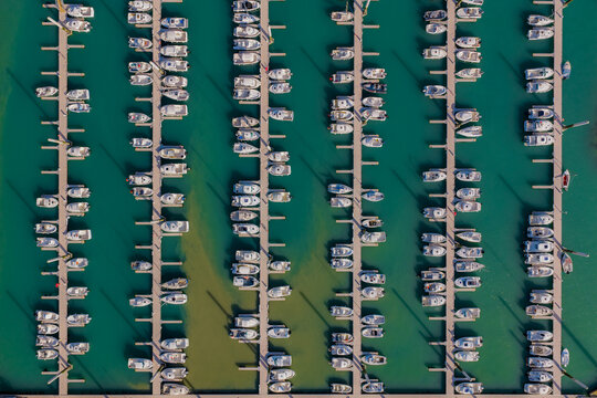 Aerial view of boats docked side-by-side in the marina, creating a rhythmic pattern against the turquoise water, Saint-Cast-le-Guildo, Brittany, France.