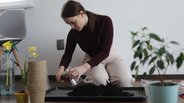 A woman is transplanting flowers into the ground at home