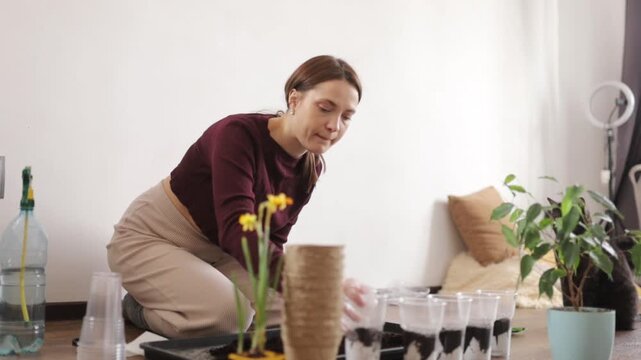 A woman is transplanting flowers into the ground at home
