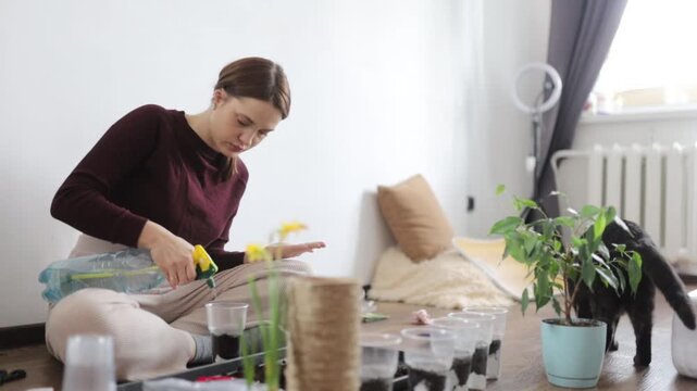 A woman is transplanting flowers into the ground at home