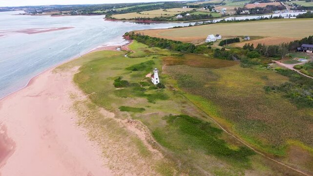 Aerial drone footage of the beautiful beach in Summerside, Prince Edward Island PEI in Canada showing the light house near the beach front and ocean on a sunny day in the autumn time