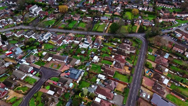 aerial panning drone shot over a suburban neighbourhood in Southampton, Hampshire named Hedge end. Shot on a quiet sunset on a cloudy winters day with many houses, fields and cars on the roads below