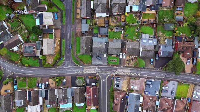 aerial panning drone shot over a suburban neighbourhood in Southampton, Hampshire named Hedge end. Shot on a quiet sunset on a cloudy winters day with many houses, fields and cars on the roads below