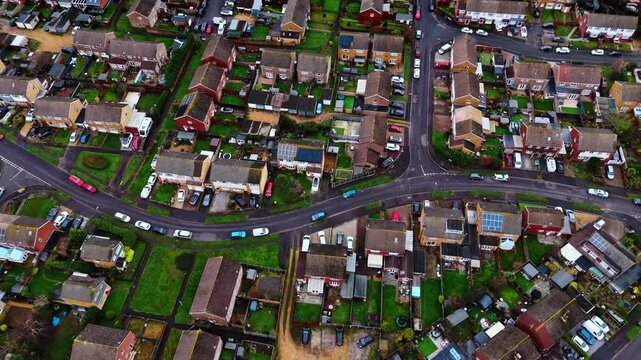 aerial panning drone shot over a suburban neighbourhood in Southampton, Hampshire named Hedge end. Shot on a quiet sunset on a cloudy winters day with many houses, fields and cars on the roads below