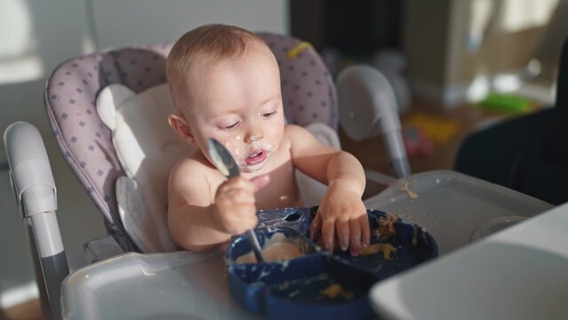baby dirty eats. happy family a child toddler concept. baby dirty sitting messing with food lifestyle at the table for feeding in the kitchen. grimy toddler in the kitchen