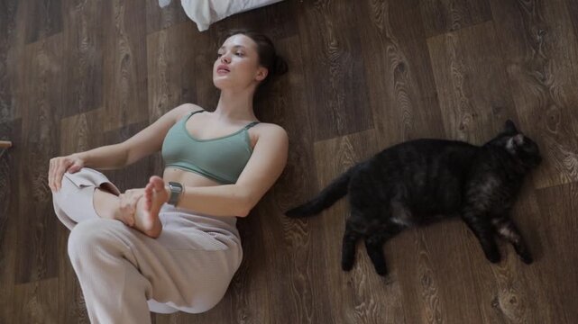 A woman with a cat doing gymnastics, yoga, and sports at home