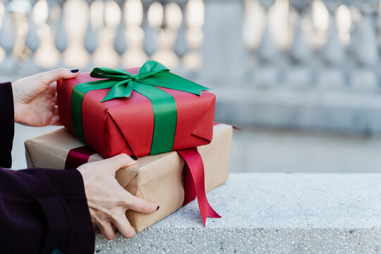 Woman holding holiday gift boxes outdoors in urban setting