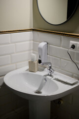 White ceramic sink and wall-mounted soap dispenser in a hotel bathroom