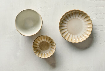 Three decorative small ceramic bowls on light painted kitchen table, top view
