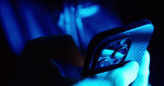 Close-up of a person using a smartphone in a dark environment at night, illuminated by blue screen light, symbolizing digital addiction, insomnia, late-night scrolling, and modern lifestyle habits.