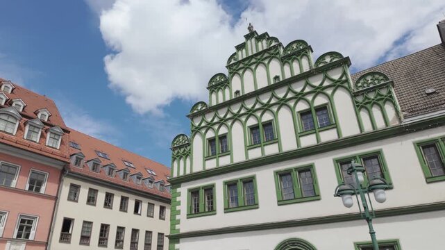 Historical market square of Weimar - Thuringia, Germany with beautiful medieval buildings. Panning right real time view of charming house facades in the old town. Romantic looking-up street scenery.
