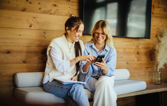 Young colleagues reviewing ideas on smartphone in startup workspace