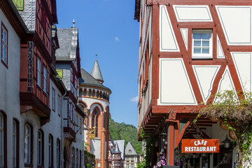 Obraz premium Charming Medieval Street in Bacharach Germany featuring Traditional Half-Timbered Houses and Wernerkapelle Gothic Church in the Rhine Valley