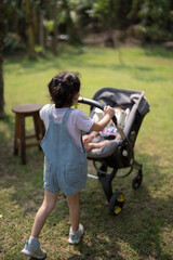 Fototapeta premium sister is pushing a stroller for her younger brother