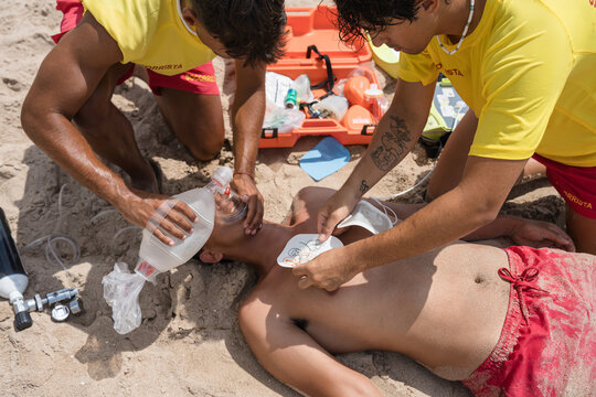Lifeguards performing cpr with defibrillator on beach