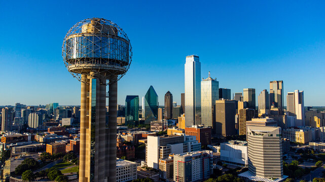 Aerial view of Reunion Tower standing tall against a backdrop of modern skyscrapers under a clear blue sky, Dallas, Texas, United States.
