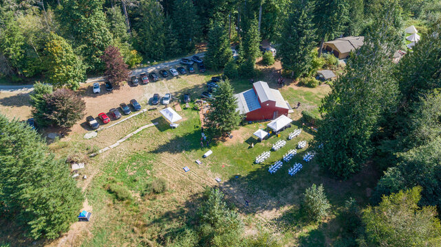 Aerial view of a picturesque scene where a red barn stands amidst lush greenery, hosting an outdoor event, Swede Heaven, Washington, United States.