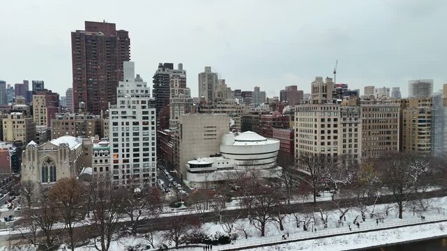 Snowy cityscape with modern and historic buildings along a frozen river in Central Park, Manhattan, New York, USA