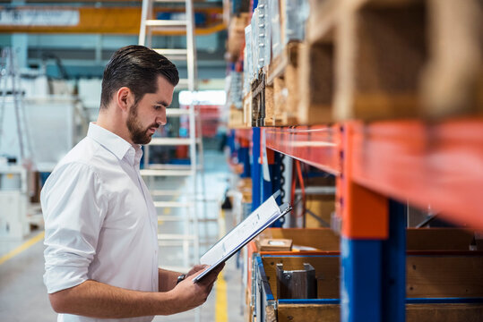 Man in factory storehouse holding folder