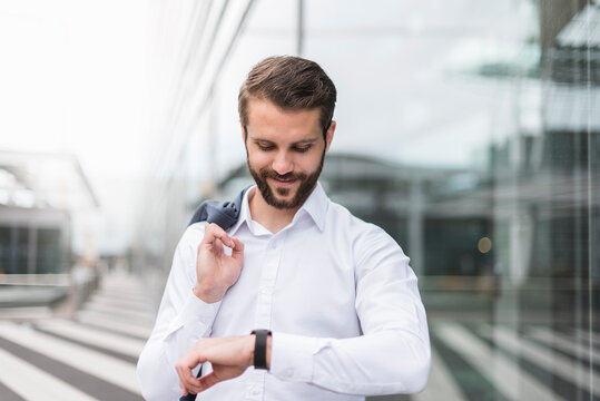 Smiling young businessman checking the time