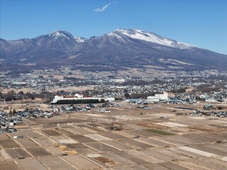 A mountain range is visible in the background of a city. The city is mostly empty, with only a few buildings visible. The sky is clear and blue, and the sun is shining brightly