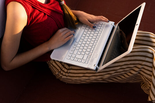 Close-up of teenage girl sitting outdoors using laptop