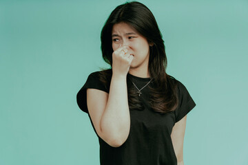Bad smell stinks. Young beautiful asian woman pinching nose with disgust. Holding breath with fingers on nose, isolated on green background.