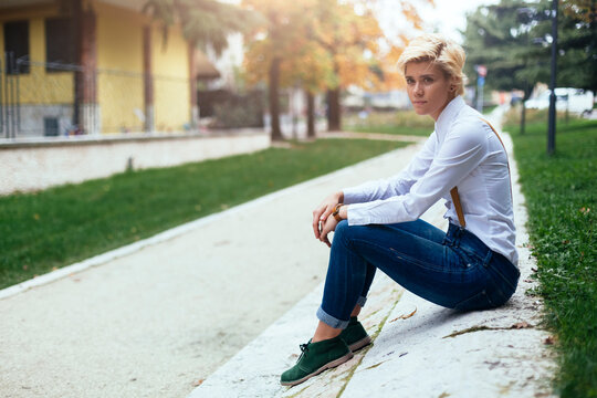 Sad teenage girl sitting at the roadside waiting