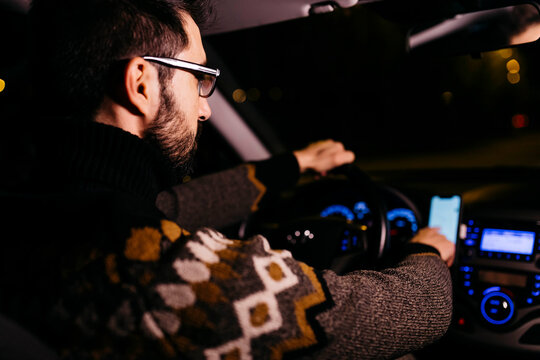 Man using cell phone with road maps in the car at night