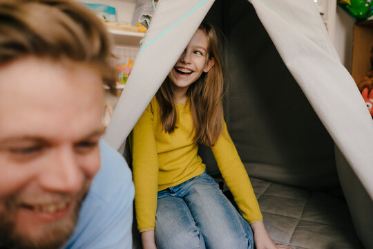 Happy father and daughter with teepee in children's room