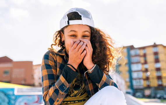 Portrait of laughing girl covering mouth with her hands