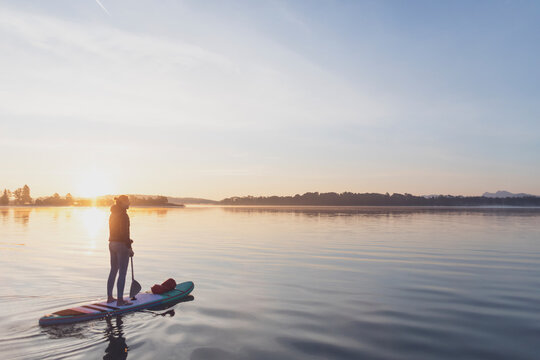 Woman standing on sup board in the morning on a lake, Germany