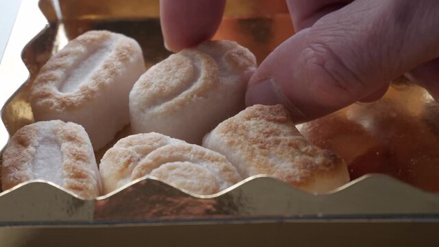 Hand selects marzipan figures, gentle moment, golden box focus