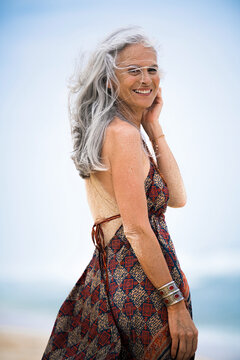 Portrait of smiling senior hippie woman with sandy back on the beach