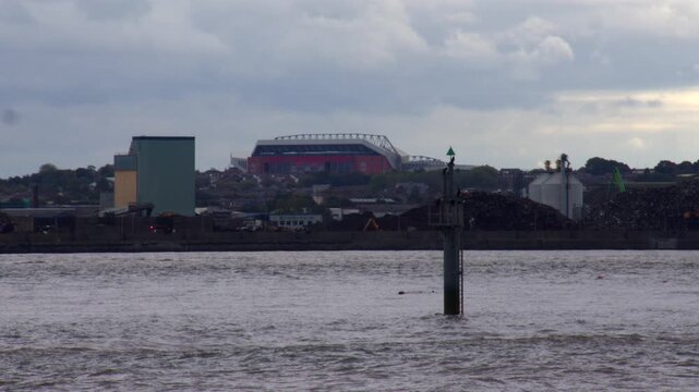 long shot of Liverpool football club stadium next to the river Mersey on a cloudy day at New Brighton beach.