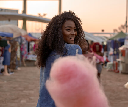Portrait of happy young woman with pink candyfloss on street market