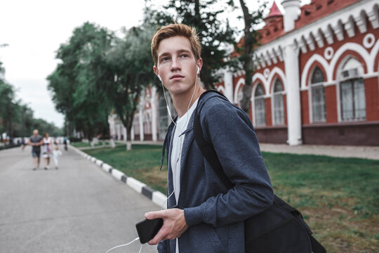 Young man with cell phone and earphones in the city