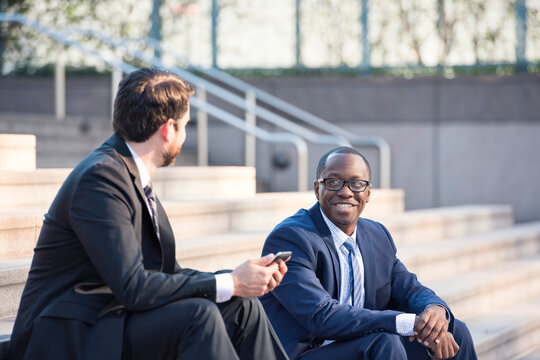 Two businessmen sitting on stairs talking
