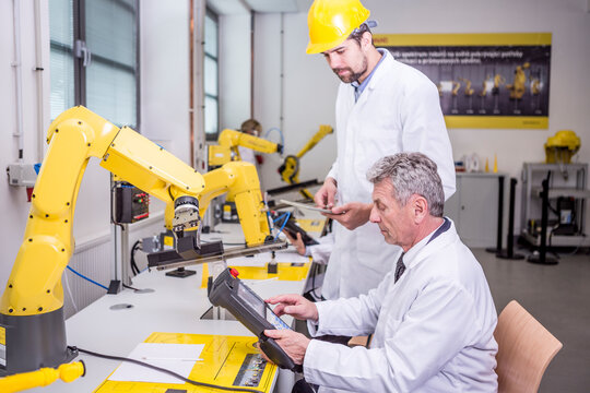 Two engineers in factory looking at device
