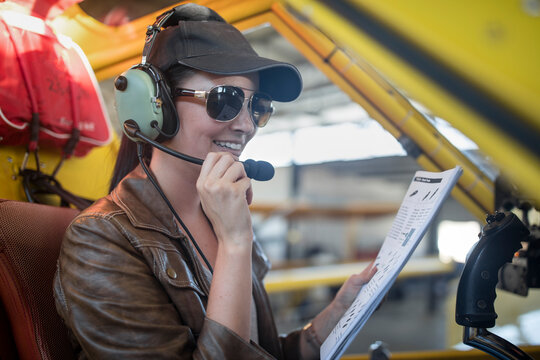 Female pilot inspecting light aircraft cockpit