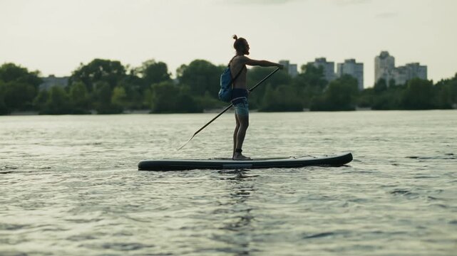 Surfer Paddling On Stand Up Paddleboard. Sportsman Exercising On Board. Leisure Recreation In Nature