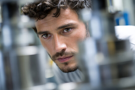 Engineer man focus inspection machinery industry worker adult beard concentration metal factory mechanic technician technology workplace job occupation professional male caucasian closeup face eye