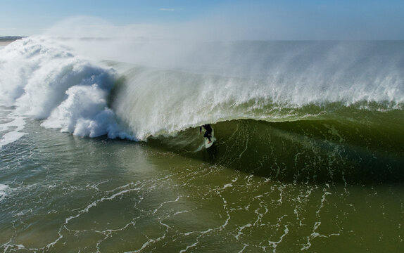 Surfer riding inside powerful barrel wave in the ocean