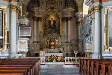 Interior of a historic Catholic church with ornate altar, religious sculptures and liturgical decorations. Sacred architecture and Christian worship space.