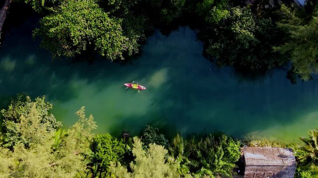 Kayakers glide across the calm, emerald waters in Koh Chang, Thailand, surrounded by lush greenery and tropical landscapes. This picturesque location offers a perfect escape for nature lovers.