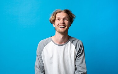 Young blond man is expressing emotions of happiness and fun, smiling broadly and laughing with an...