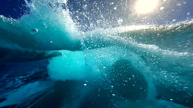 Ocean wave crashes underwater with bubbles rising to surface in clear blue water 20