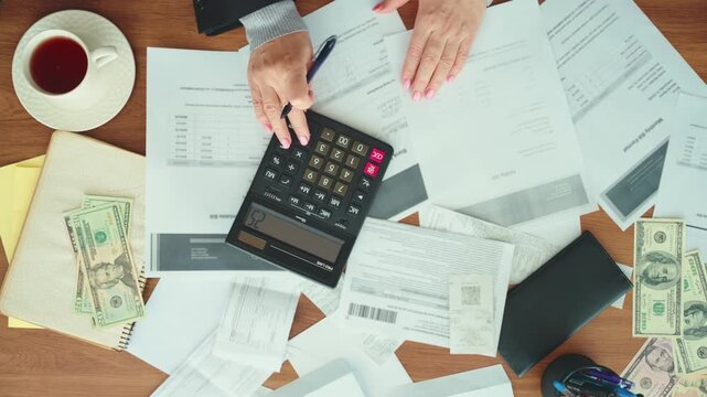 Hands accountant working at office desk using calculator planning corporate budget. Stressed woman taking notes checking utility bills taxes bank account balance. calculating expenses indoors top view
